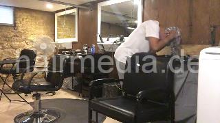 986 A lone in a row. African barberette washing her hair in salon forward over backward bowl