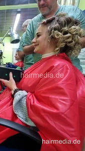 2303 VanessaH 3 chewing metal rollers wetset and hood dryer by barber in red cape - vertical video
