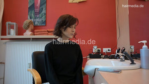 1180 MichelleB by barber 1 waiting a lone in barberchair in Berlin salon in black large vinyl cape