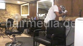 986 A lone in a row. African barberette washing her hair in salon forward over backward bowl